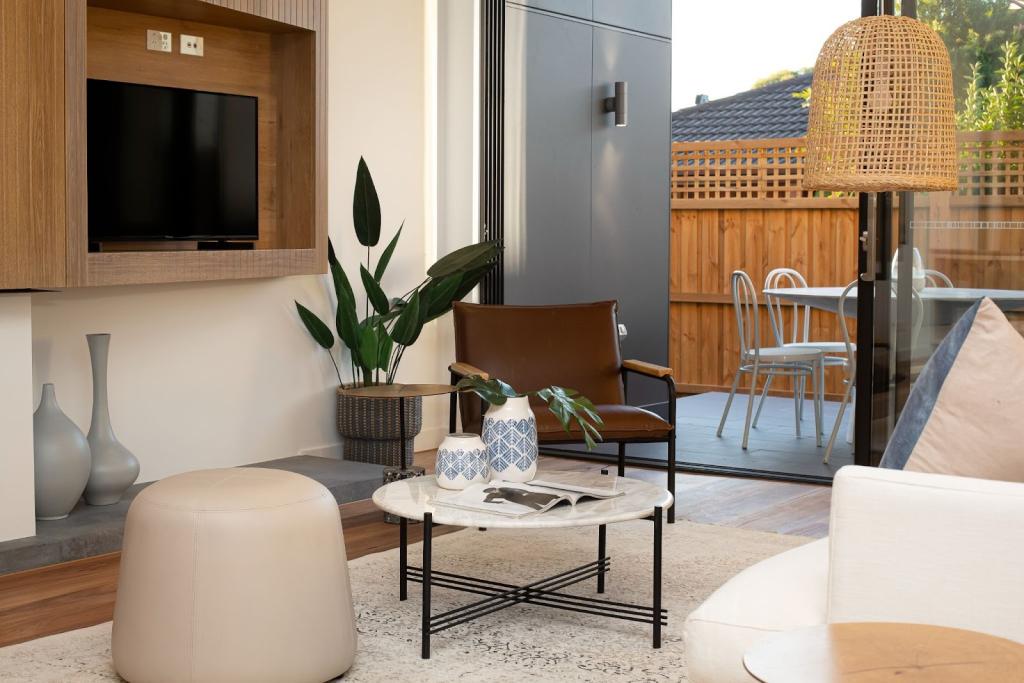 Sleek living room remodeled with earth tones, opening to a patio with a wood fence and a rattan pendant light